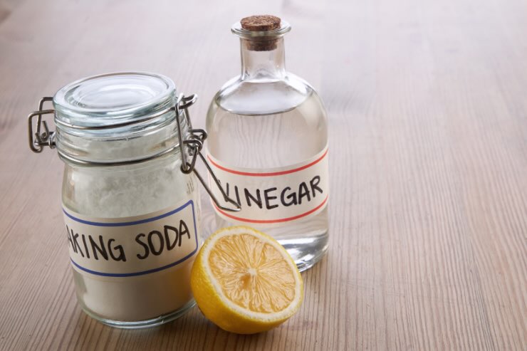 barattoli di vetro con bicarbonato, aceto e mezzo limone 