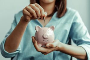 donna che mette una moneta dentro al salvadanaio