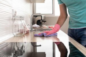 mano con panno viola che pulisce piano cottura